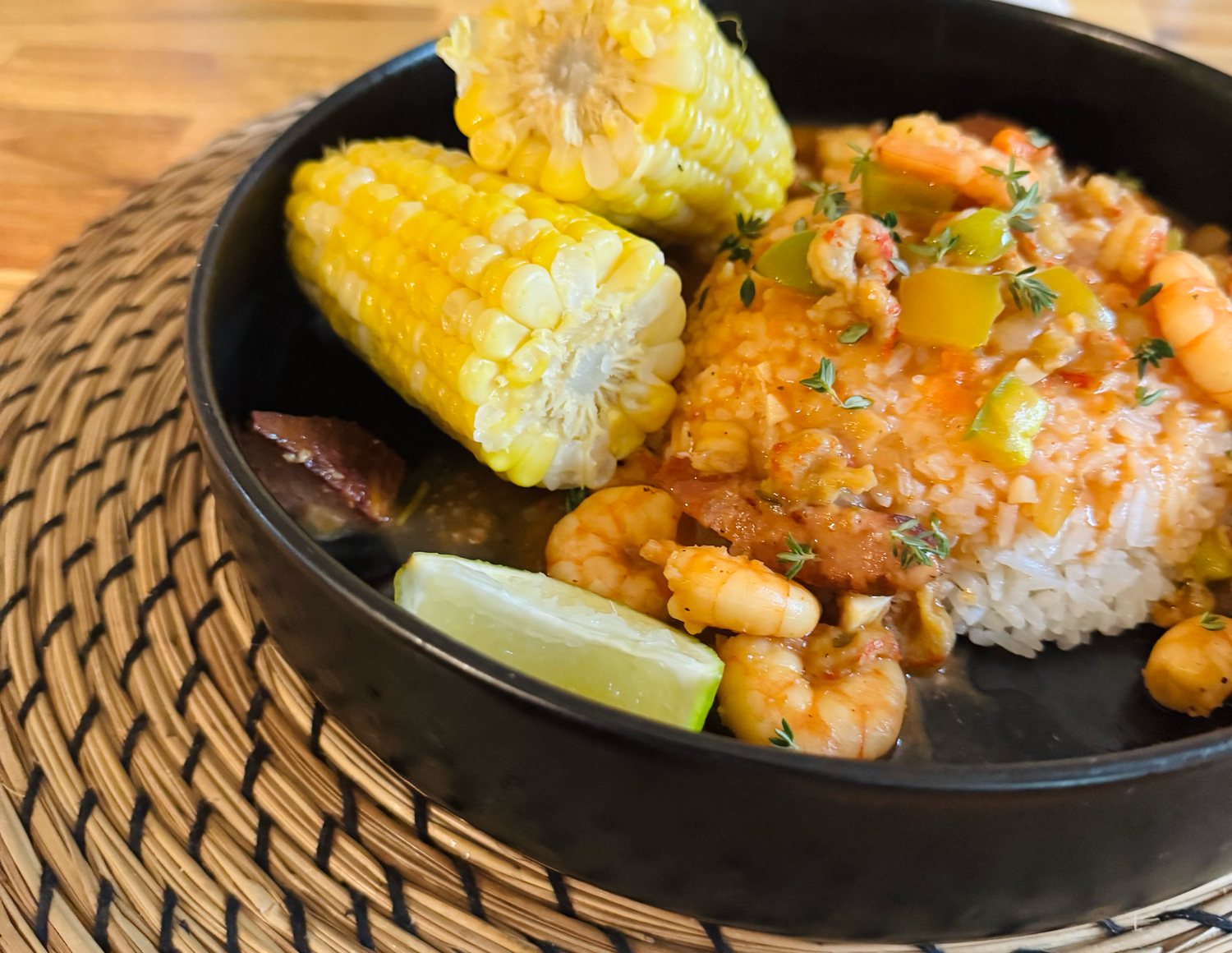A finished bowl of rice, shrimp, crawfish, sausage and sweet corn, served at the table